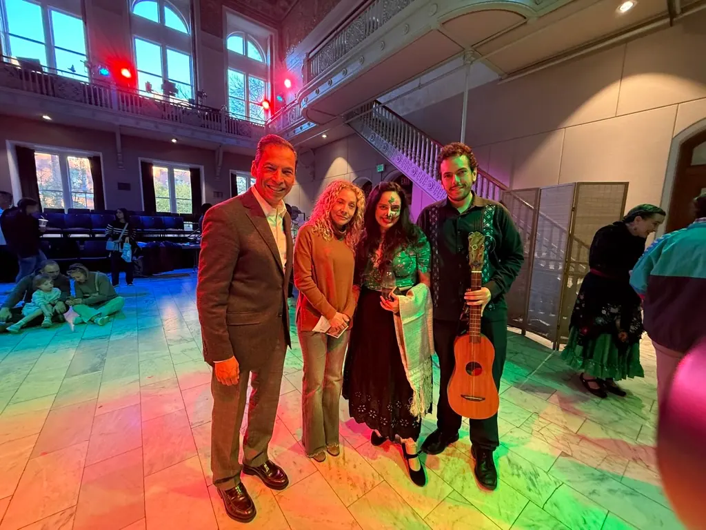 Artists and organizers under colored lights at the Día de Muertos celebration