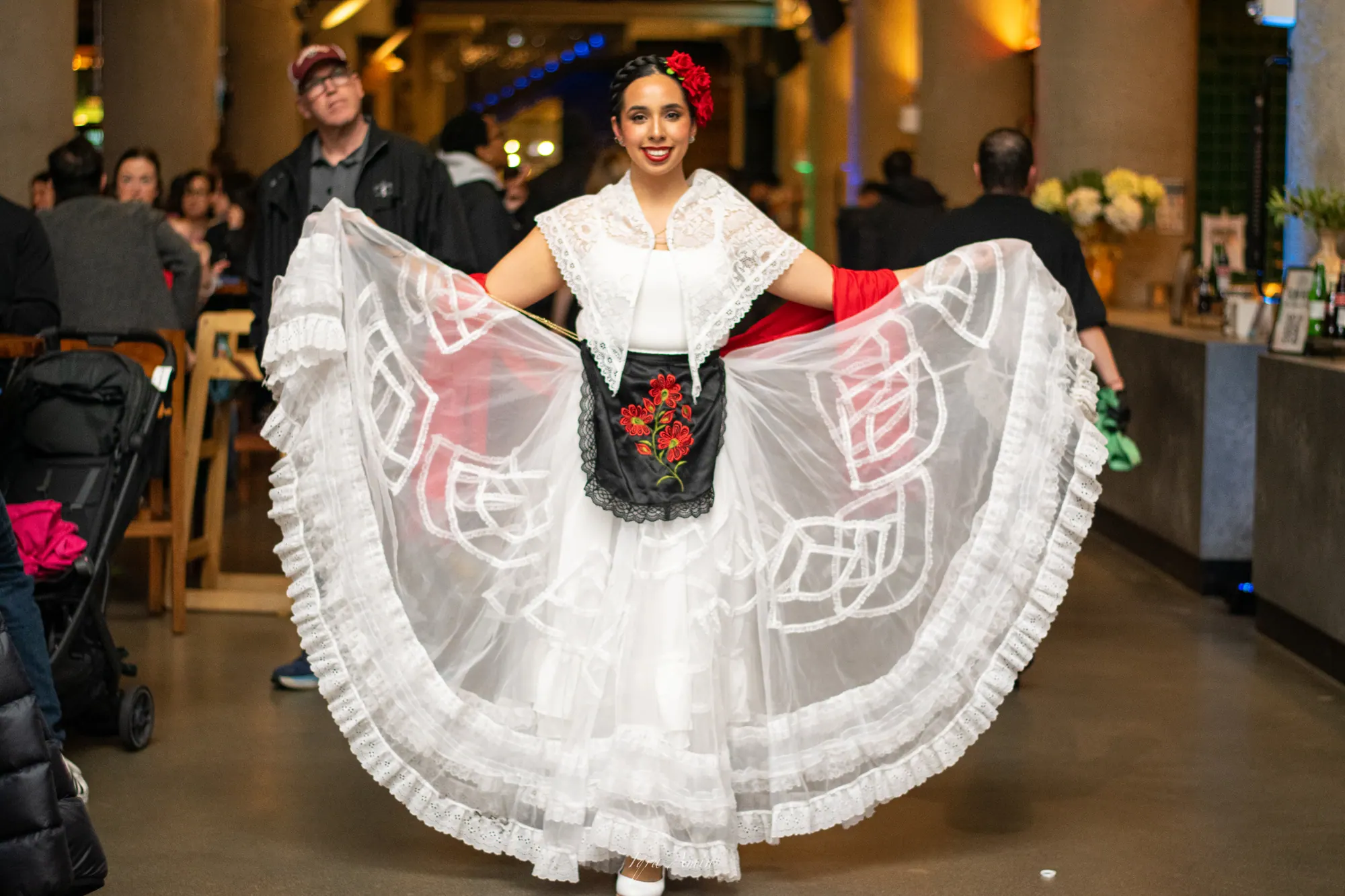 Folk dancer in a white lace dress opening her skirt like wings at Time Out Market
