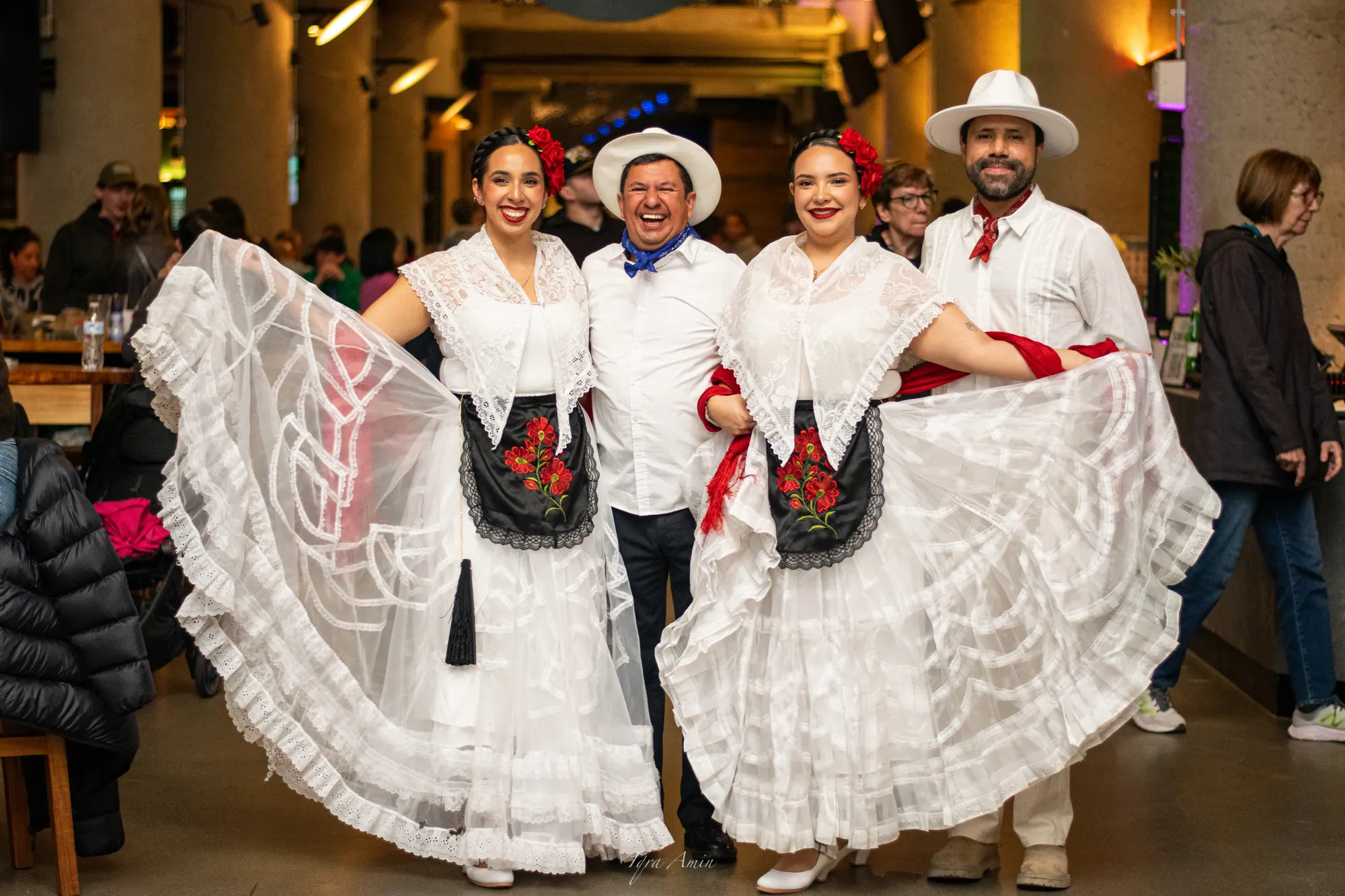 Two folk dancers in white lace dresses and two musicians smiling at Time Out Market