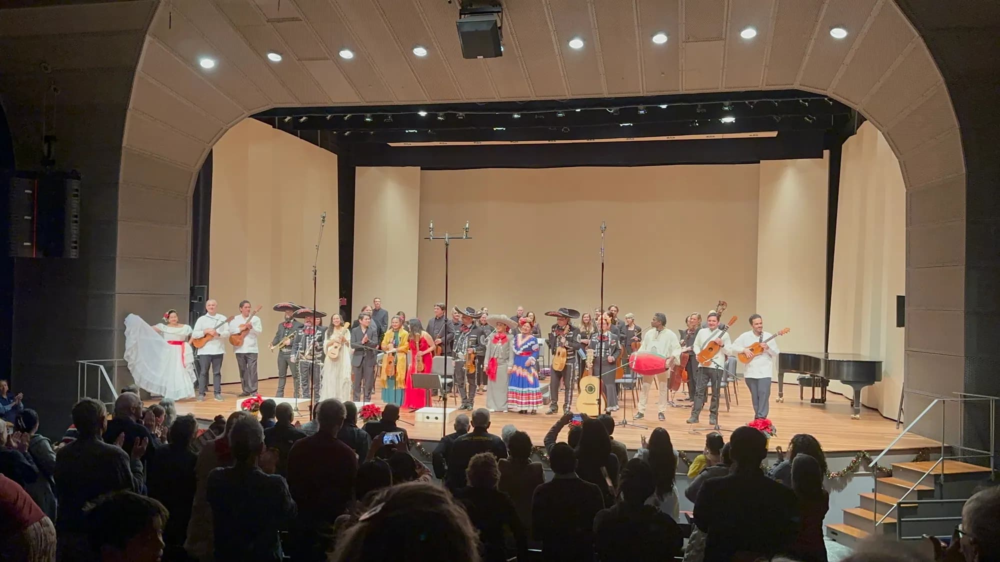 Orchestra UNIDOS, mariachi and folk dancers taking a bow on stage before a full house